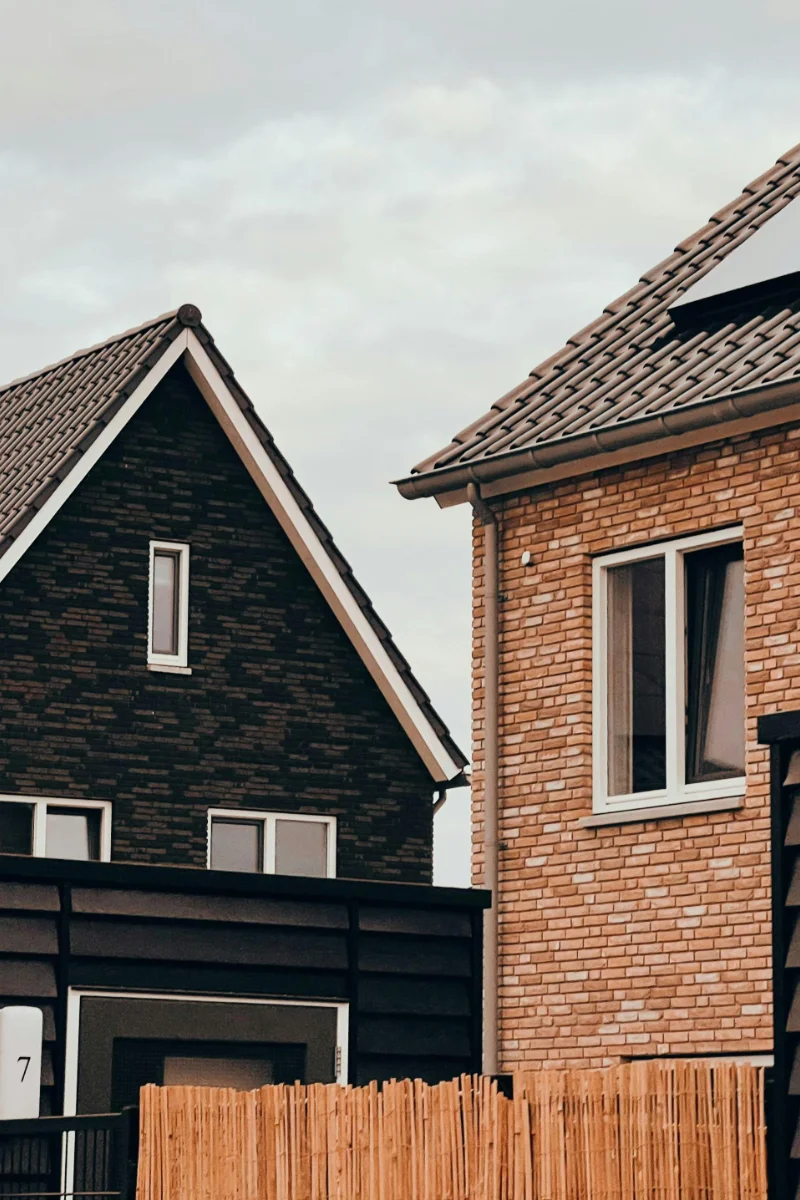 Modern brick new build homes with tiled roofs, large windows and wooden fencing.